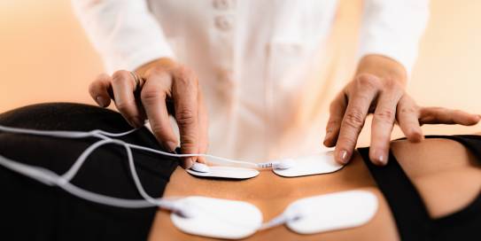Elektrotherapie mit Elektroden auf dem Rücken einer Patientin