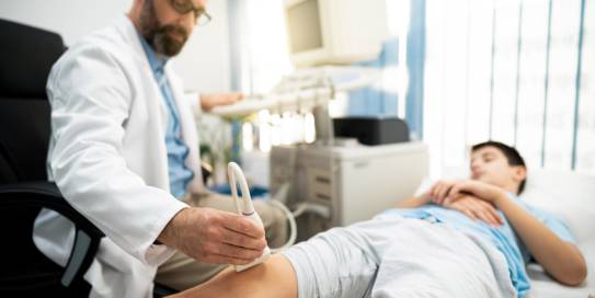Arzt untersucht Knie mit einem Ultraschallgerät
