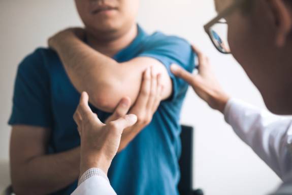Physiotherapeut untersucht den Ellenbogen eines Patienten