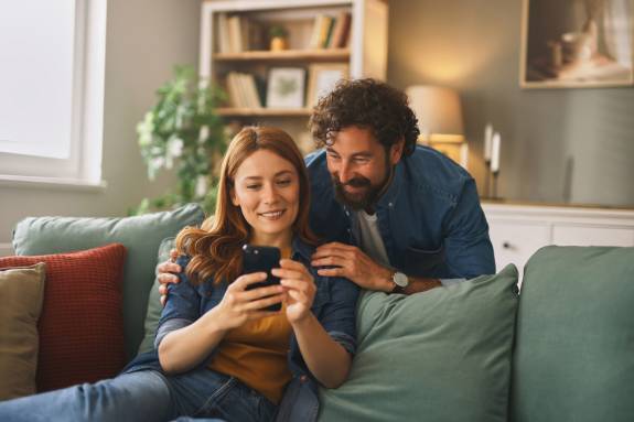 Frau und Mann schauen lächend auf ein Smartphone