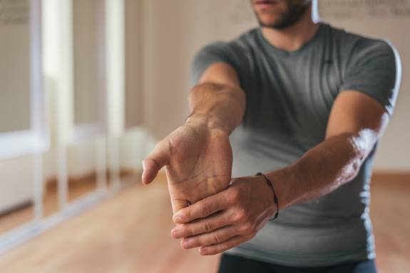 Sportlicher Mann dehnt seinen Unterarm nach dem Training