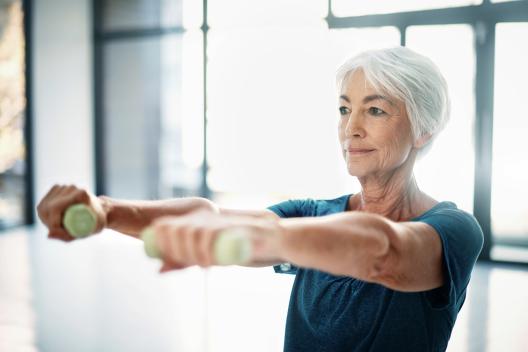 Ältere Frau trainiert mit Hanteln in der Physiotherapie